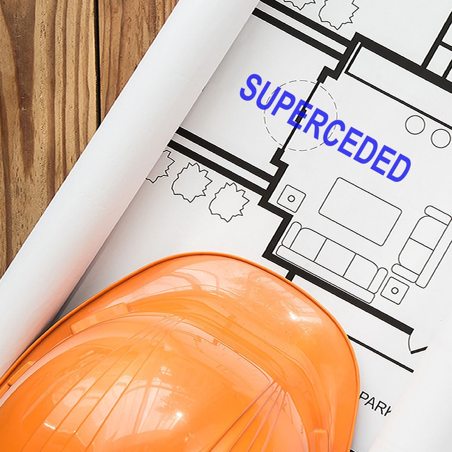 Orange hard hat on architectural blueprints with superceded stamp, construction plan review concept