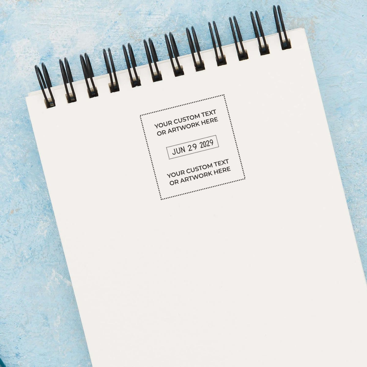 Blank spiral notebook mockup with customizable cover text on a blue textured background, ideal for calendar, planner, or stationery design.