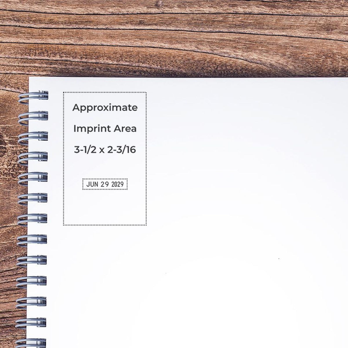 Spiral notebook mockup on rustic wood background with approximate imprint area and date stamp placeholder for custom branding.