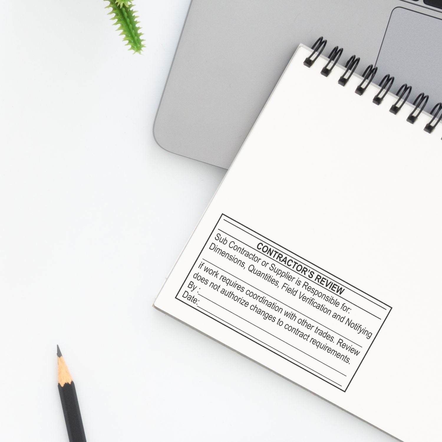 Construction contractor review notebook next to laptop and pencil on a clean white desk top view