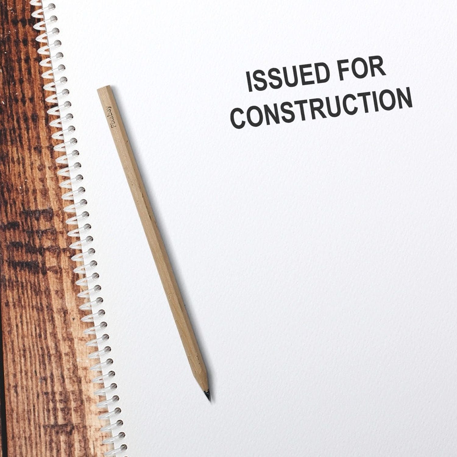 Notepad with pencil and Issued for Construction text on white paper.