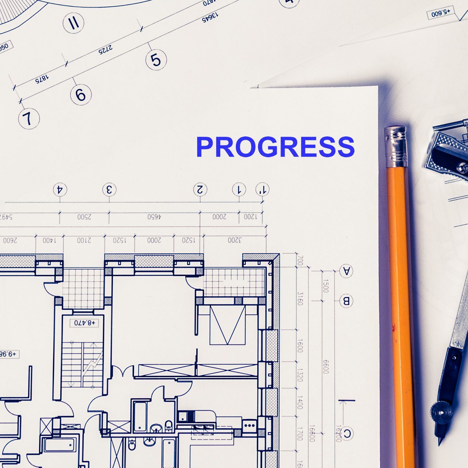 Architectural blueprint with the word progress, pencil, and drafting tools on a building floor plan.