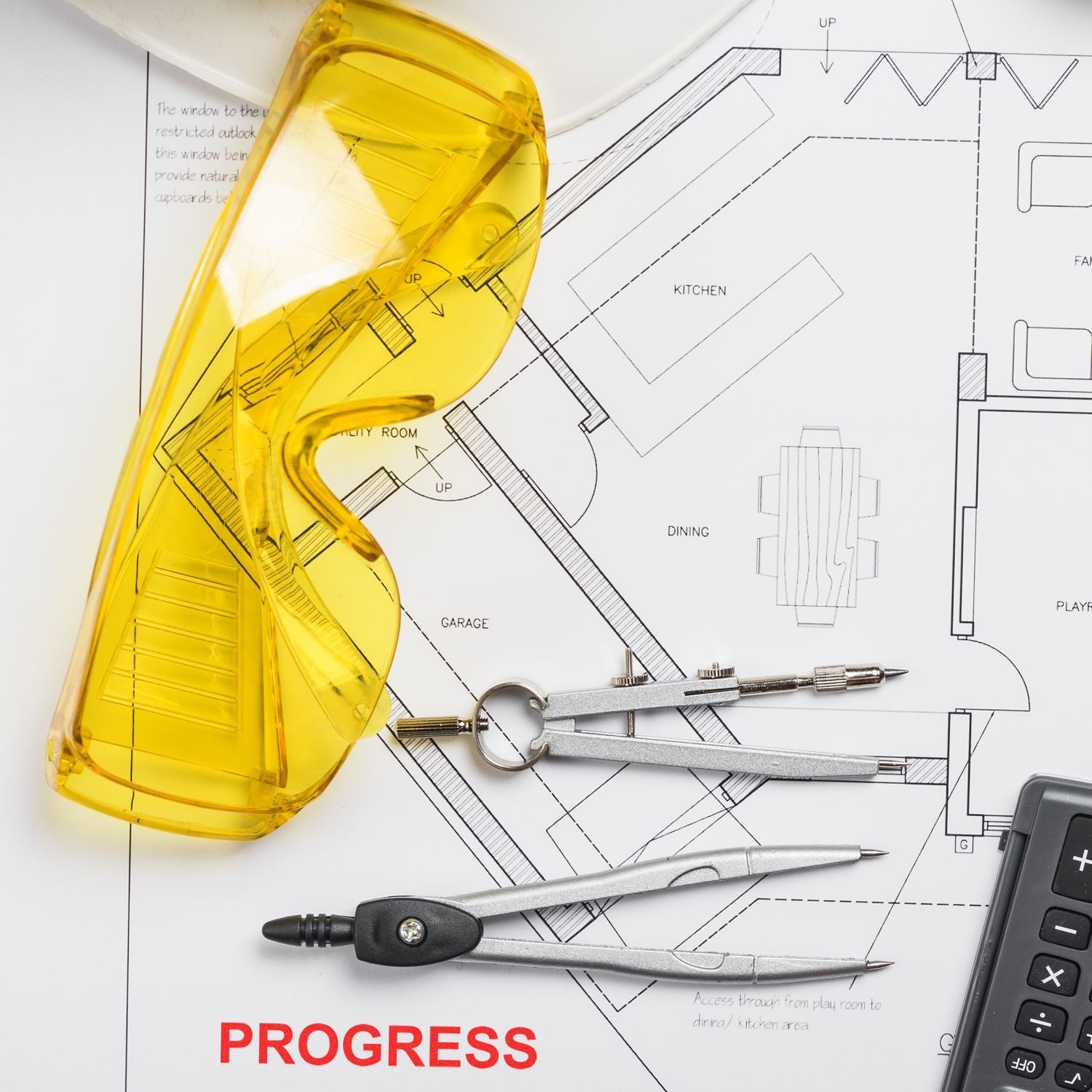 Architectural floor plan with drafting tools, compass, calculator, and yellow safety glasses on a home design blueprint with progress text.