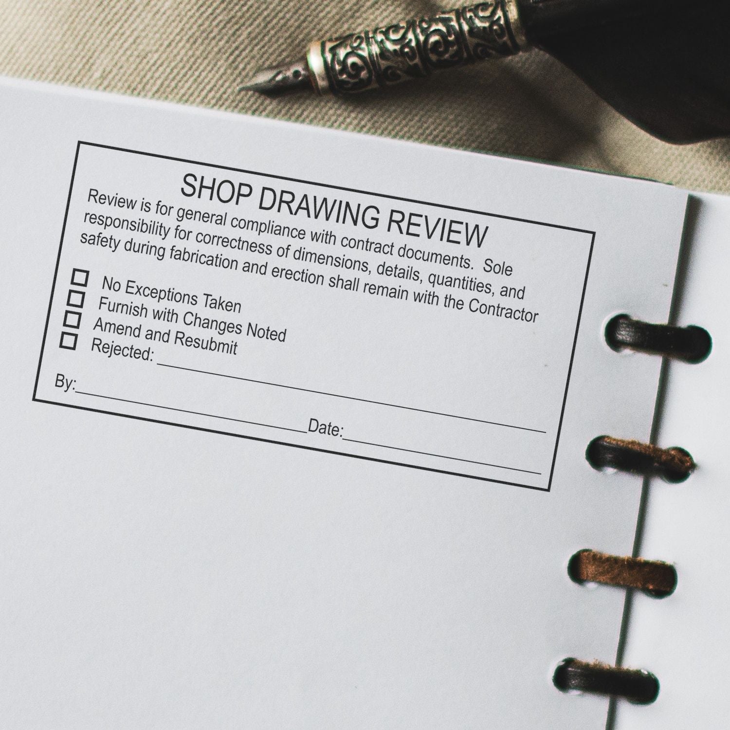 Close-up of shop drawing review form in a construction binder with pen, used for contractor approval and compliance review.