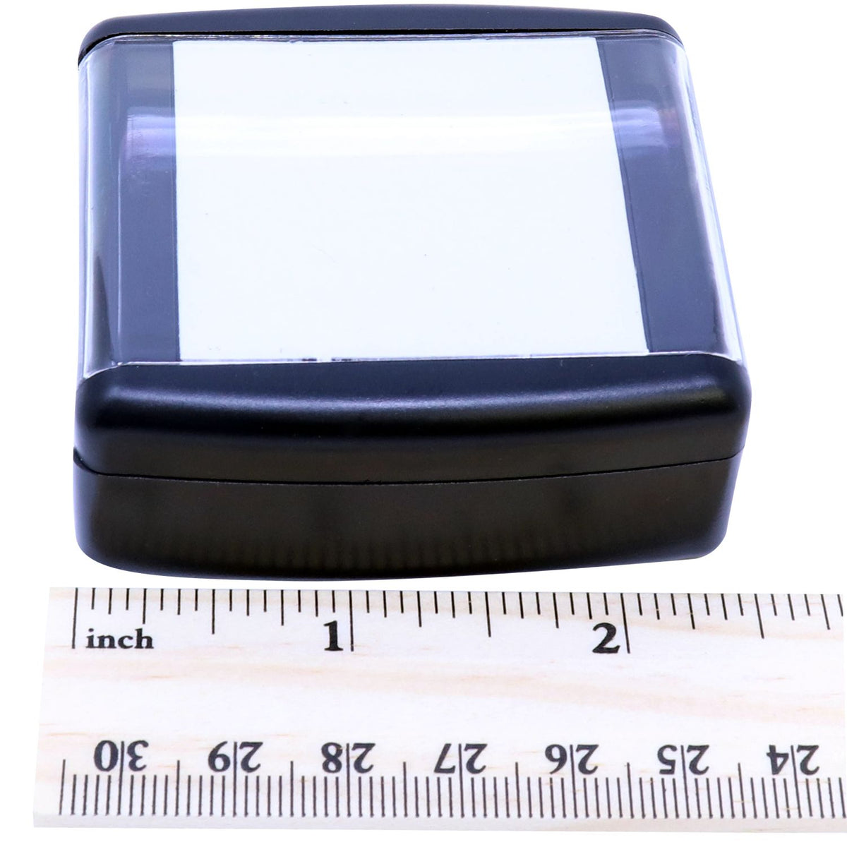 Close-up of compact blue-black plastic case with clear window, shown with inch ruler for size measurement.