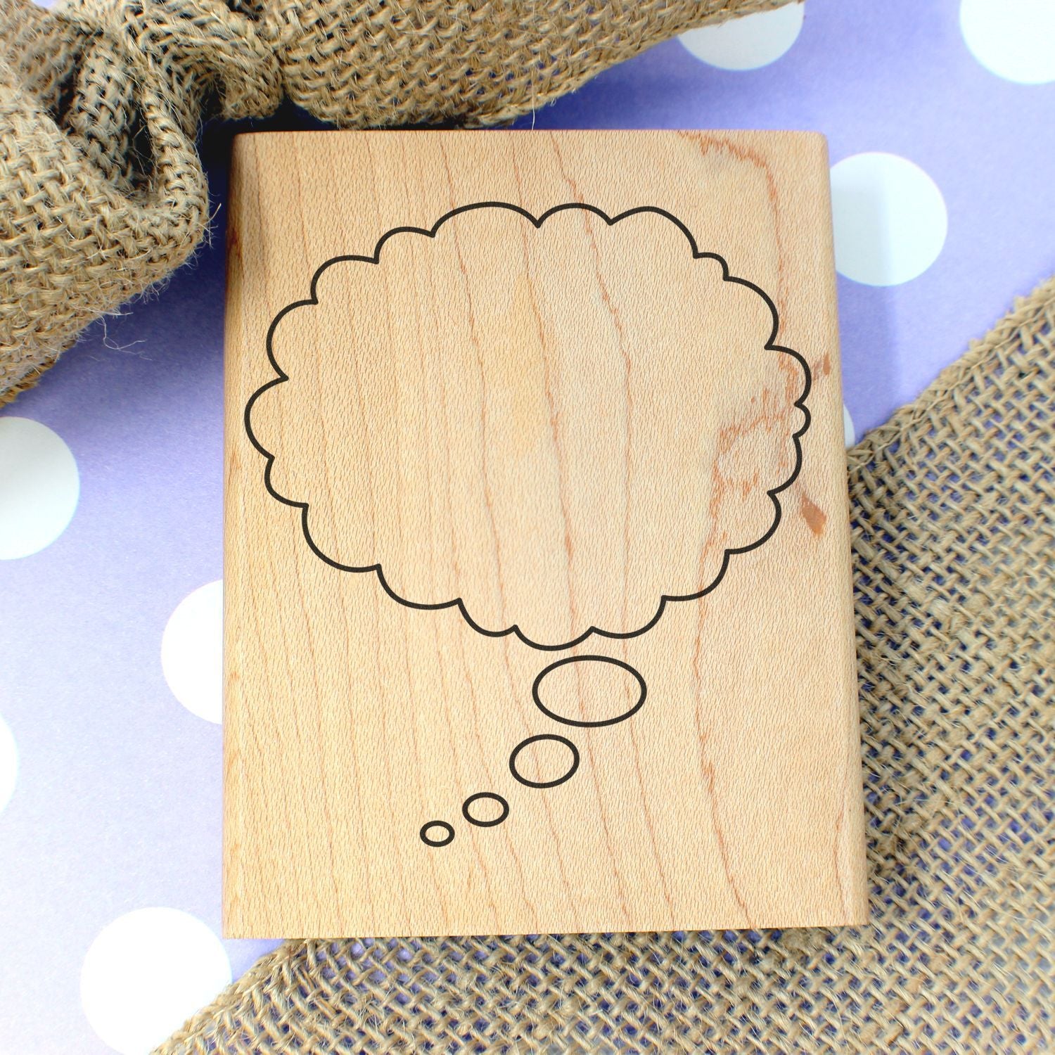 Wooden thought bubble stamp on polka dot background with burlap fabric, handmade craft supply close-up