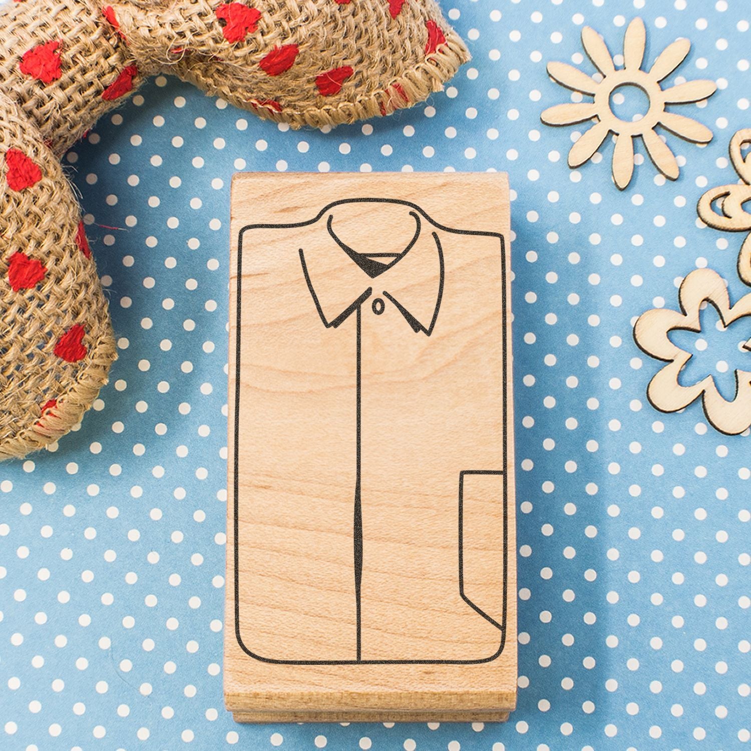 Wooden shirt stamp block on blue polka dot background with rustic rope and floral craft decorations