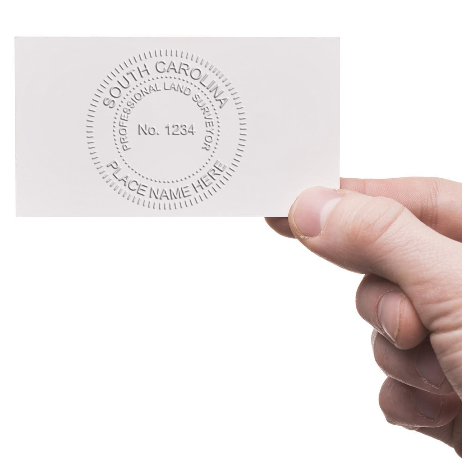 Hand holding an embossed South Carolina professional land surveyor seal card with sample license number.