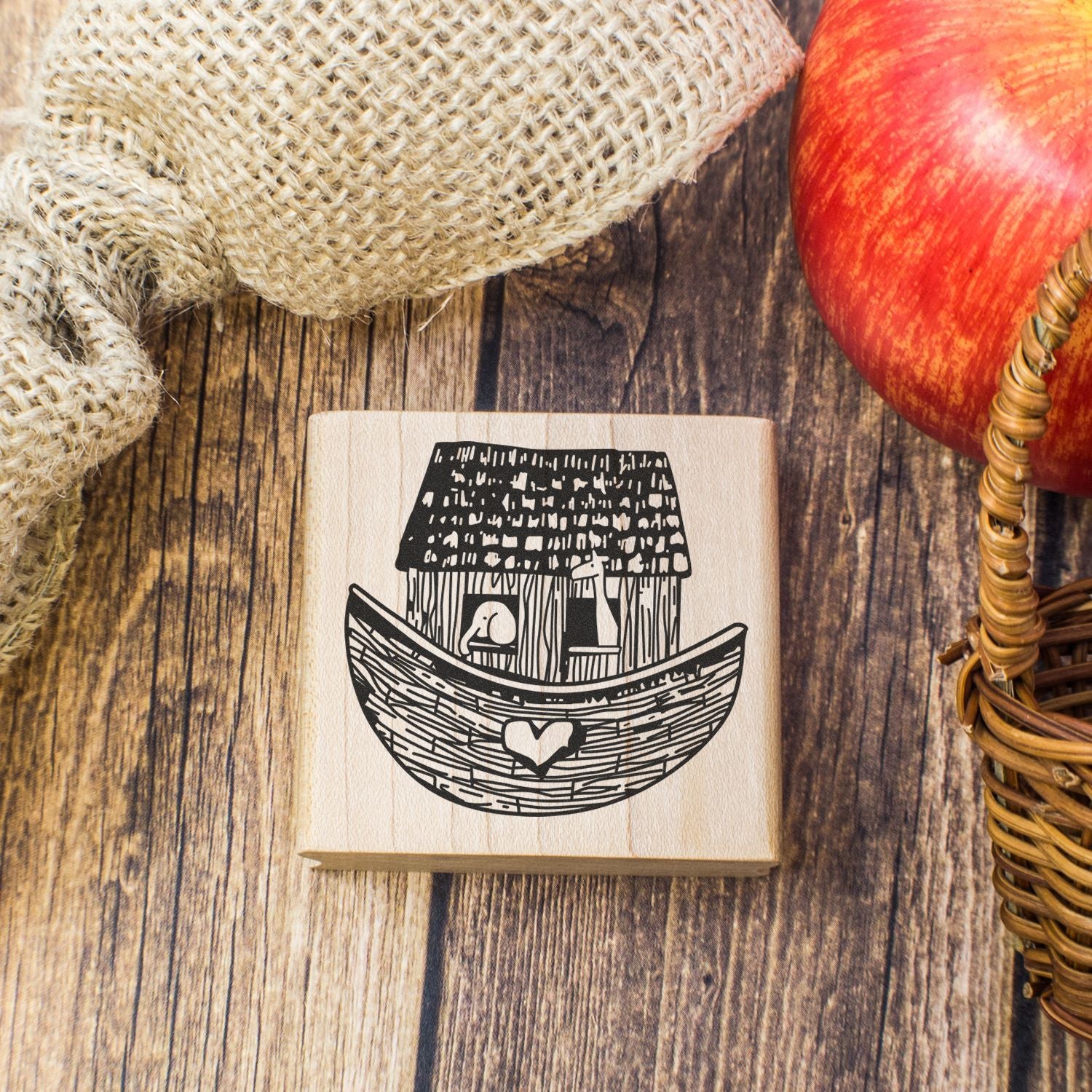 Rustic wooden stamp with Noahs Ark design on a farmhouse wood background, styled with burlap and a red apple.
