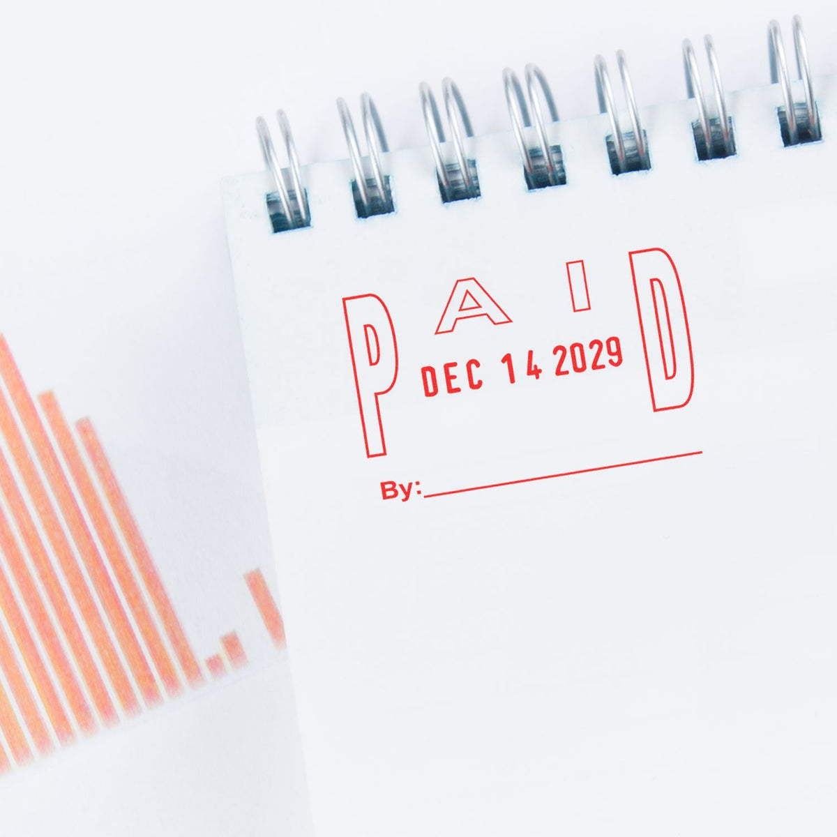Close-up of a spiral calendar page marked PAID with the date Dec 14, 2029, symbolizing bill payment and financial planning.