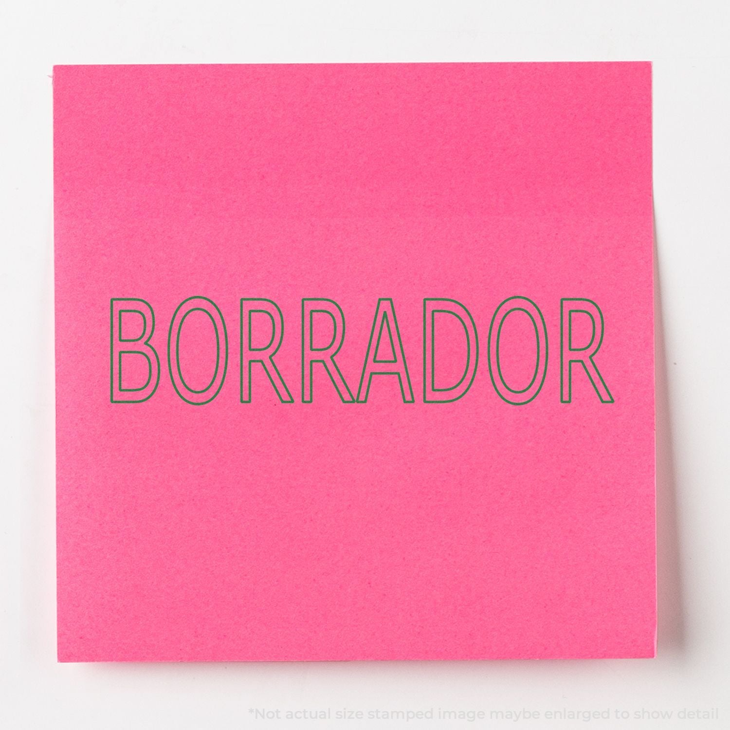 Pink stationery card with green outlined text BORRADOR, Spanish word for eraser or draft, studio typography photo on white background.