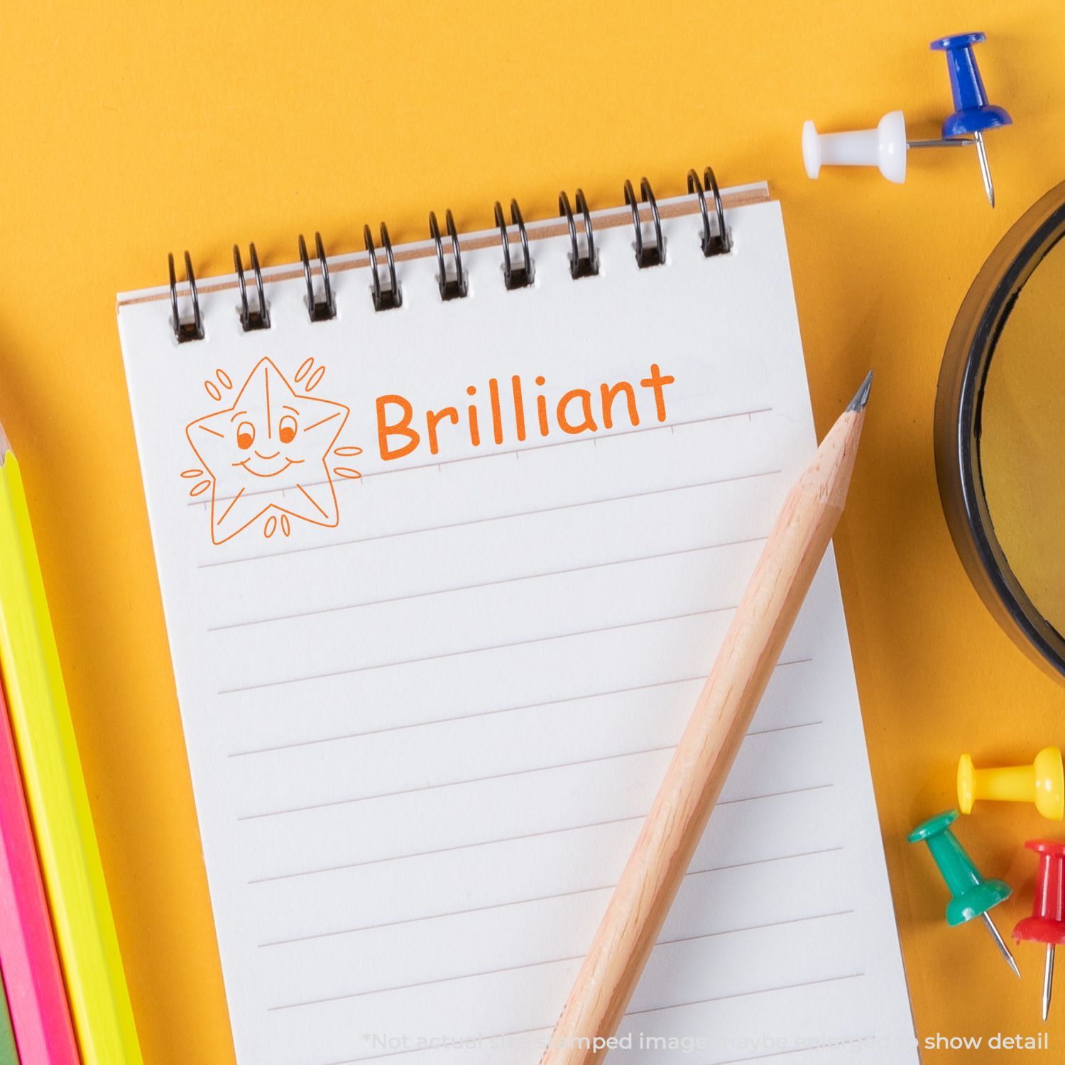Back-to-school notebook labeled Brilliant with pencil and pushpins on yellow background, inspiring study and writing daily notes.