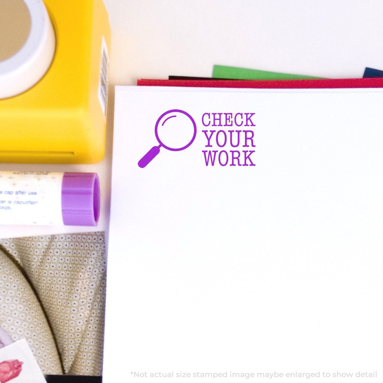 Colorful office stationery with a Check Your Work magnifying glass stamp on a notebook page.
