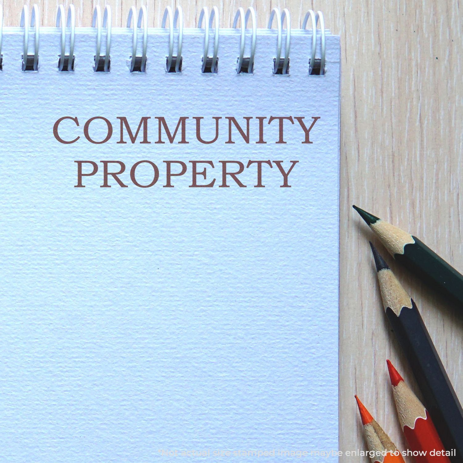 Notebook page with Community Property text beside colored pencils on a wooden desk.