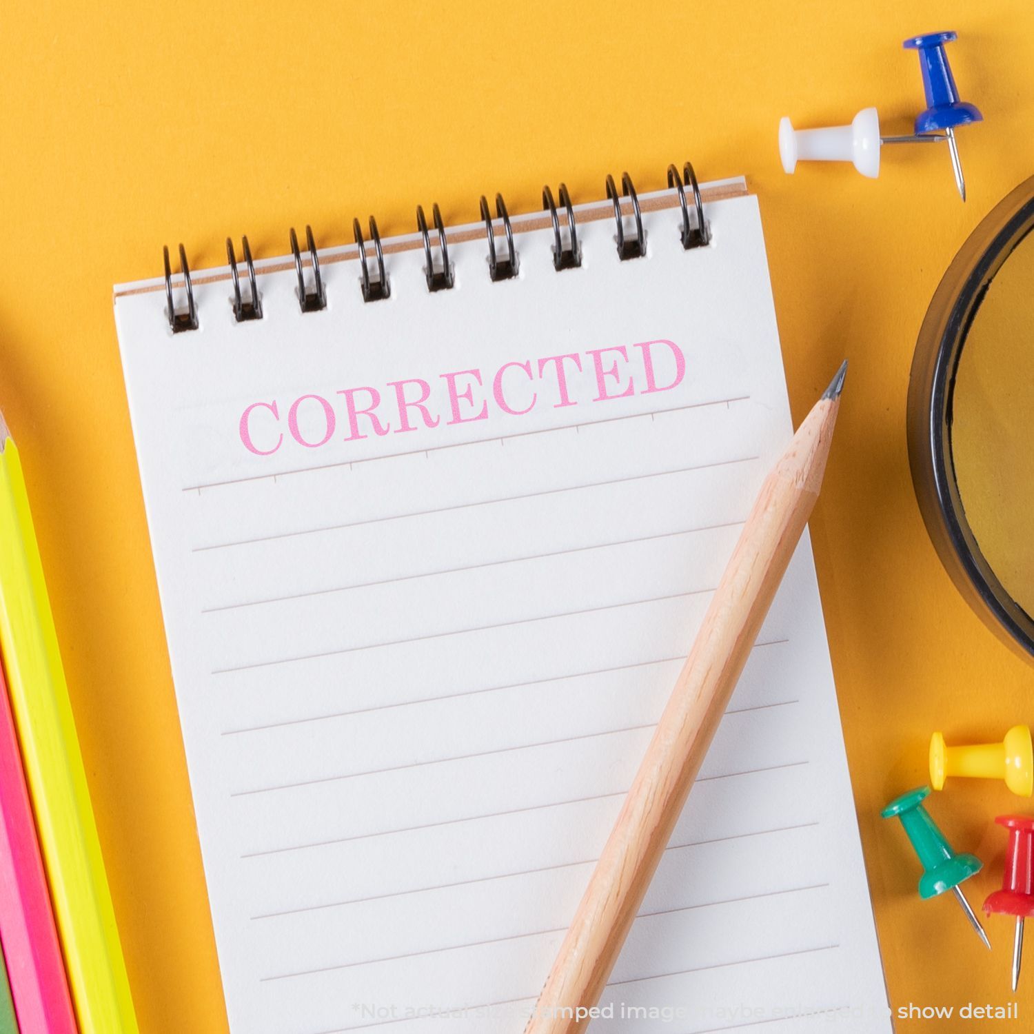Corrected notepad with pencil, push pins, and magnifying glass on a yellow background.