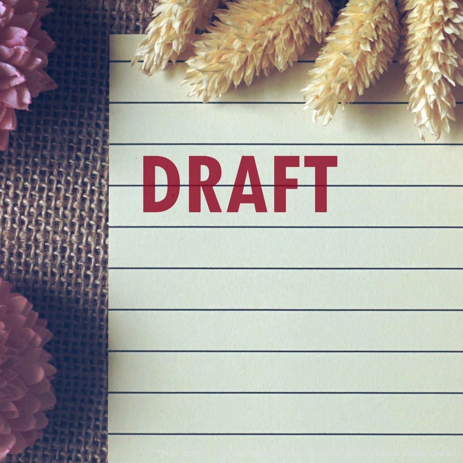 Blank lined notepad labeled DRAFT with decorative dried flowers and rustic burlap background, stationery concept image