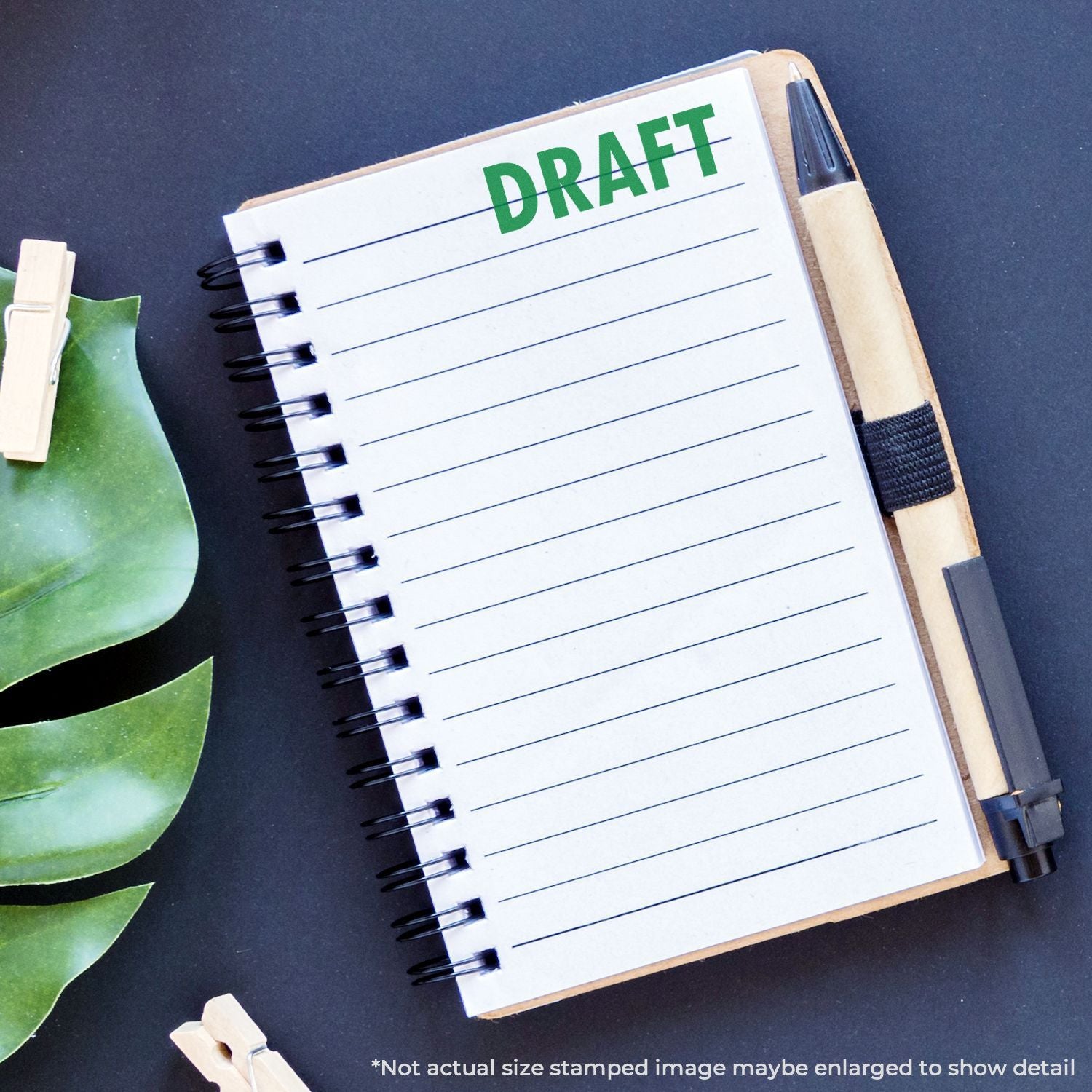 Draft notebook page labeled DRAFT with pen and binder clips, showing writing, planning, and editing process in an office workspace.
