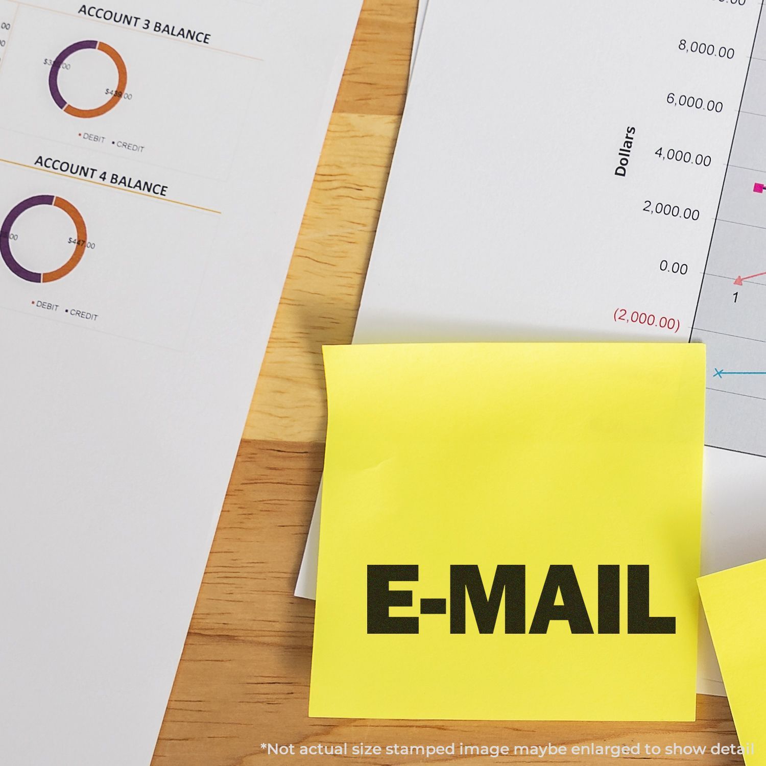 Yellow sticky note labeled E-MAIL on financial reports with charts and account balance graphs on a wooden desk.