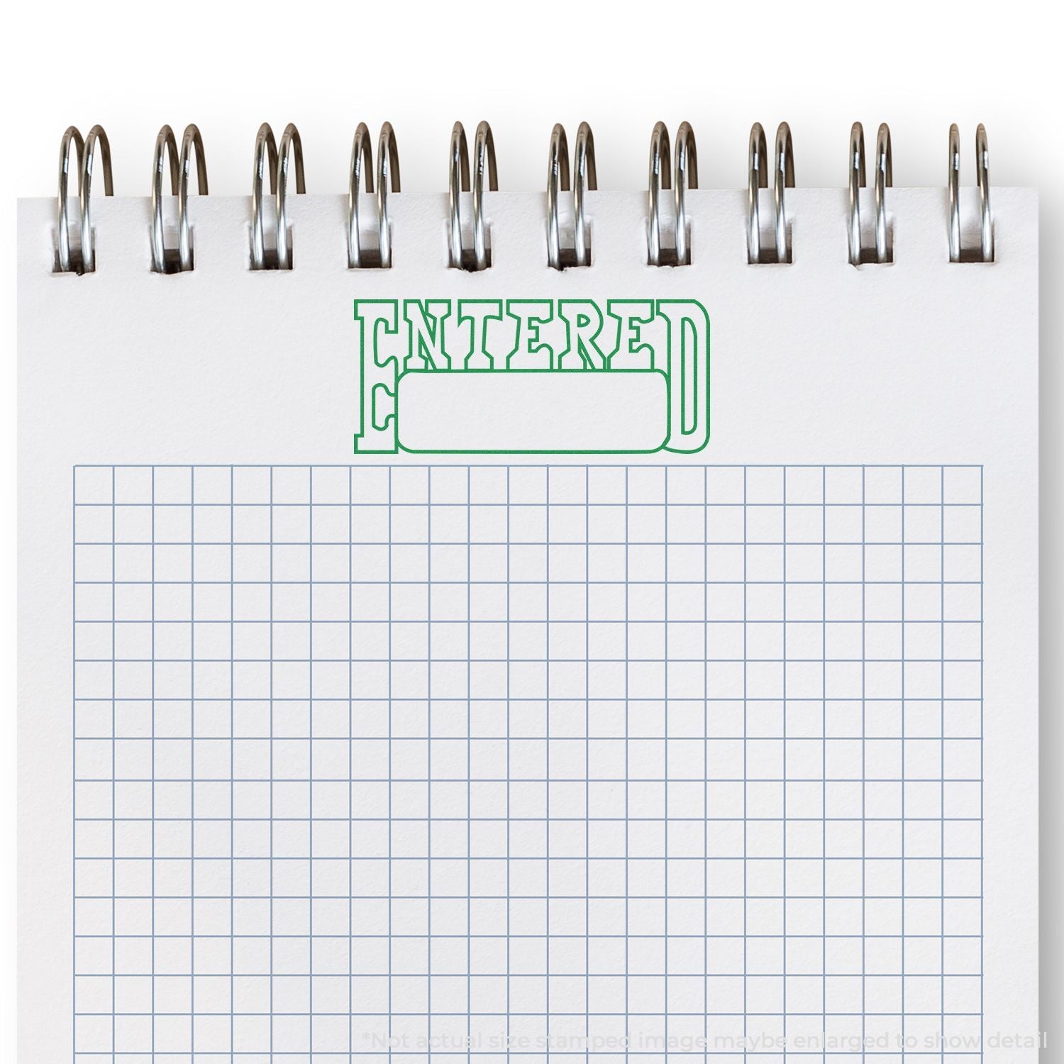 Green 'ENTERED' date stamp on white lined notebook grid with metal handle, illustrating office paperwork entry approval and record keeping.