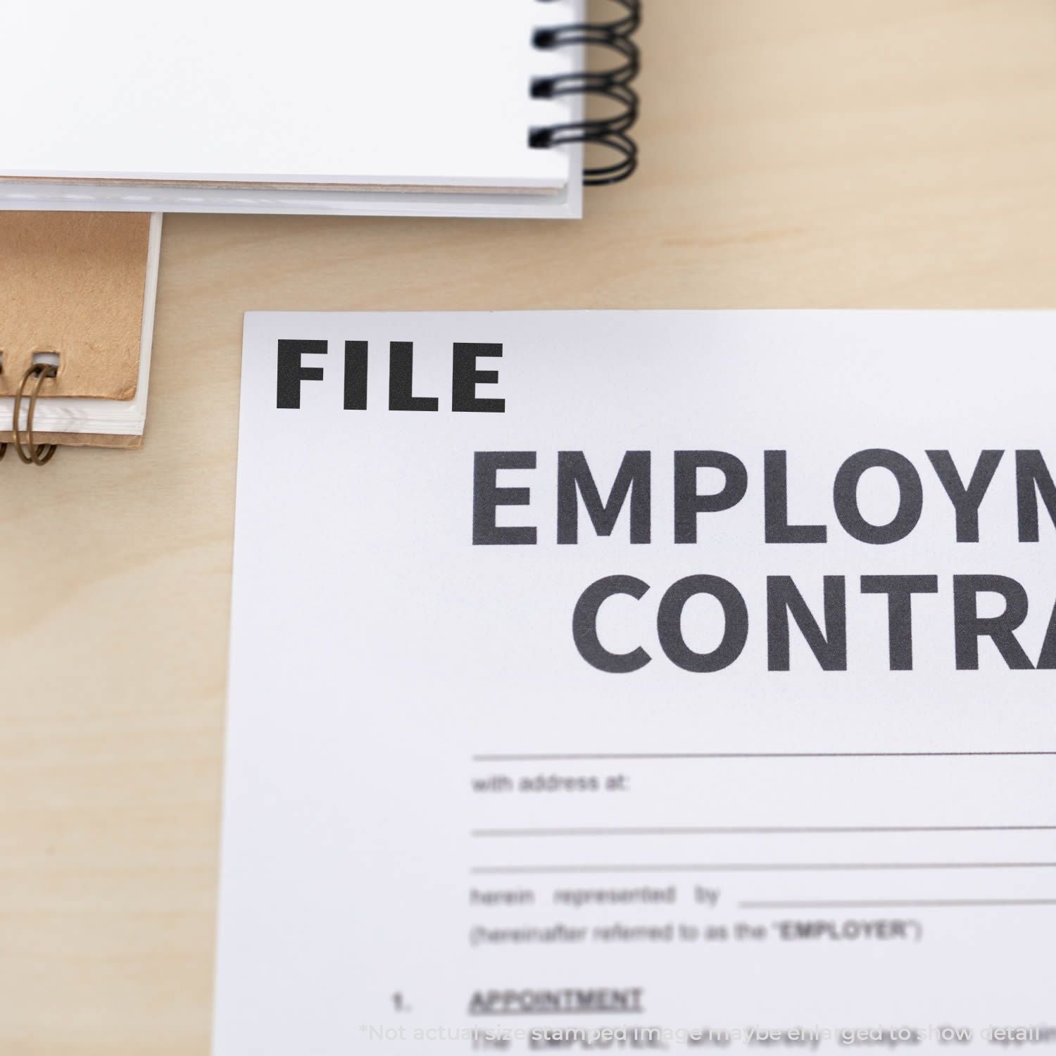 File employment contract document on a desk with notebook and office paperwork.