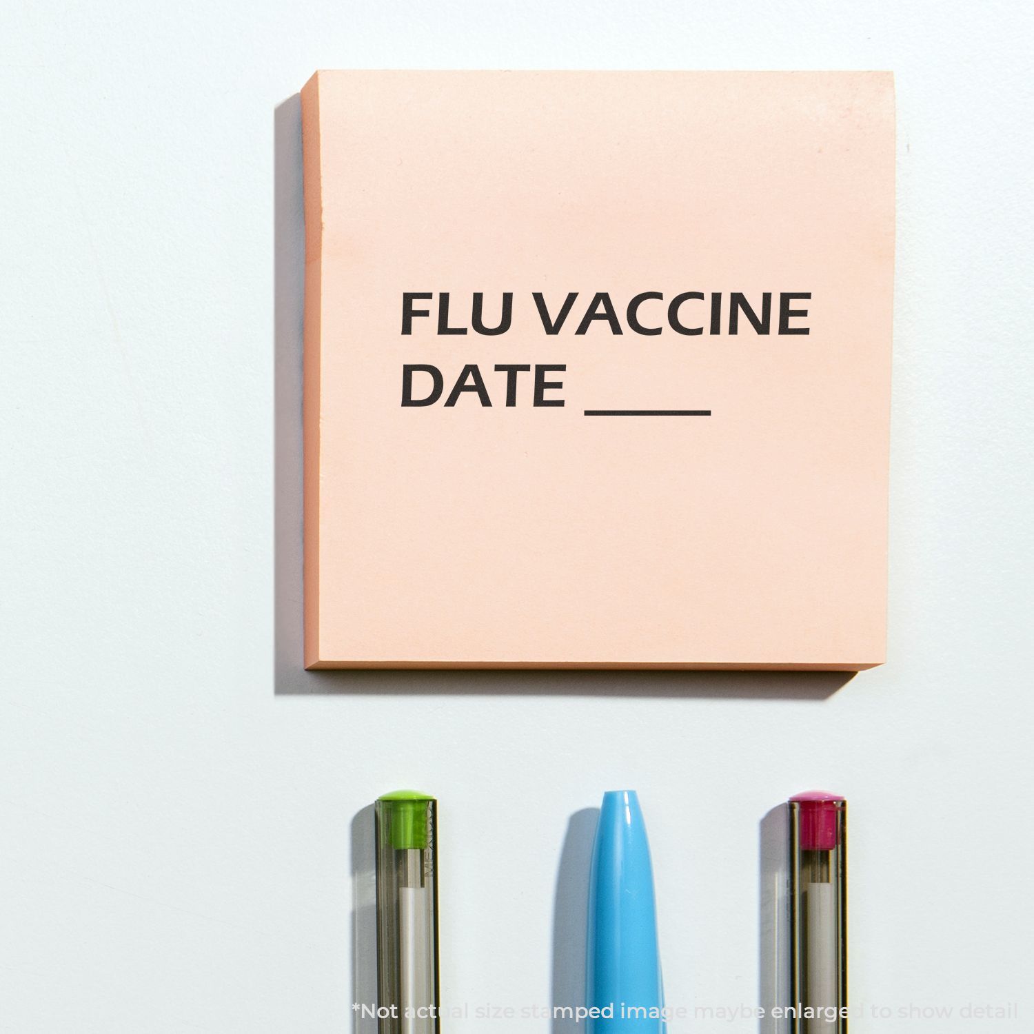 Flu vaccine date reminder note with pens and highlighter on white background