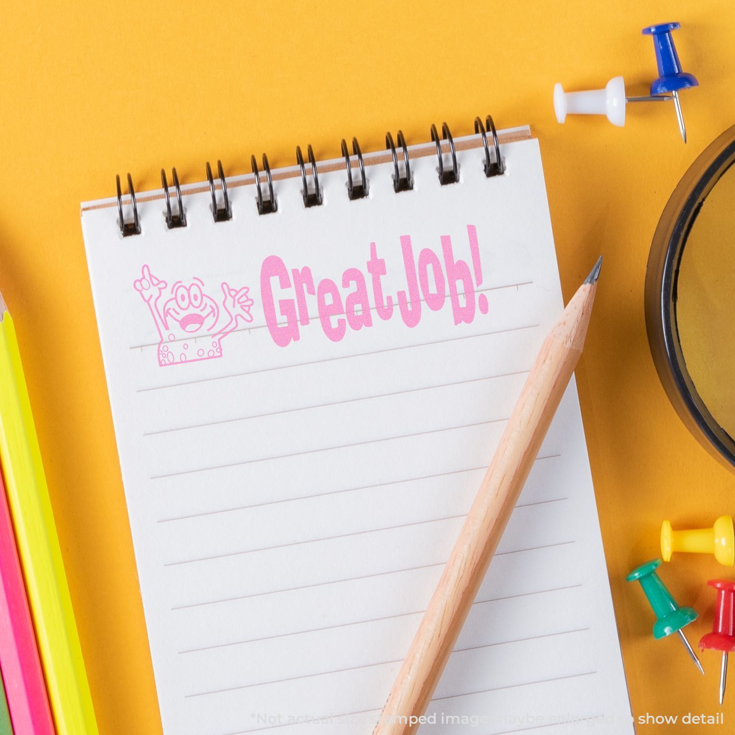 Motivational Great Job! notebook on yellow background with pencil and colorful stationery pins.