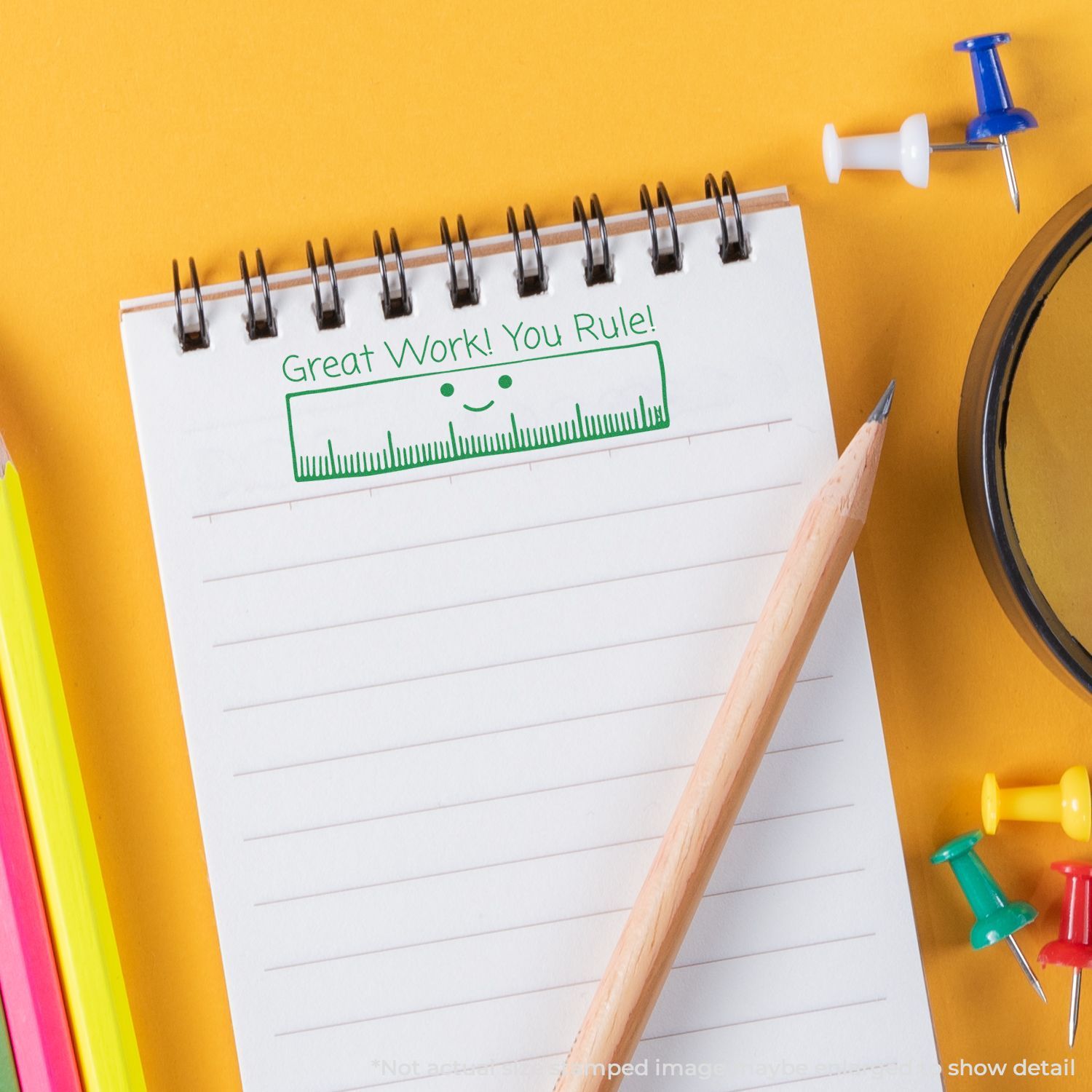 Notepad with Great Work! You Rule! message, pencil, and colorful push pins on a yellow background.