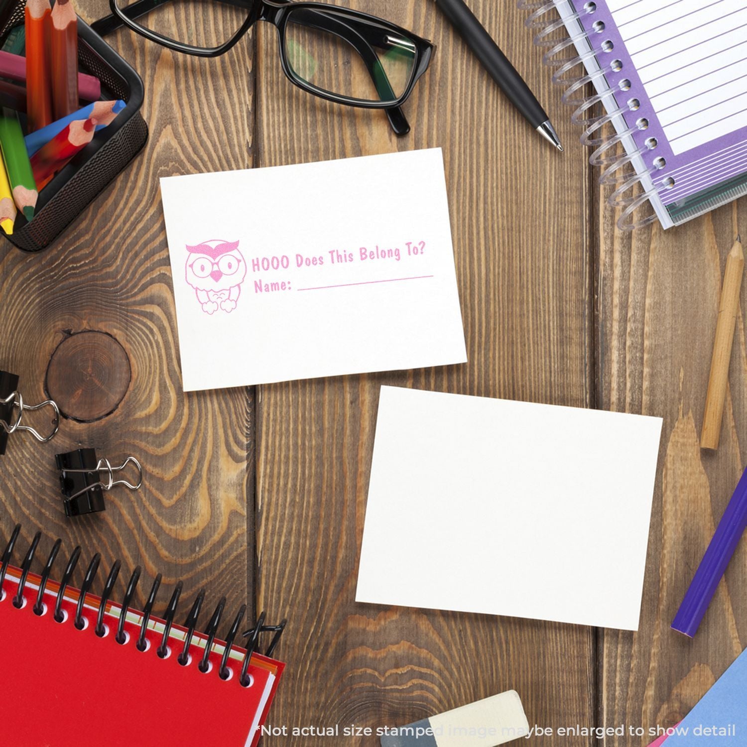 Kids classroom name tag worksheet HOOO Does This Belong To? on wooden desk with pencils, glasses, and notebooks