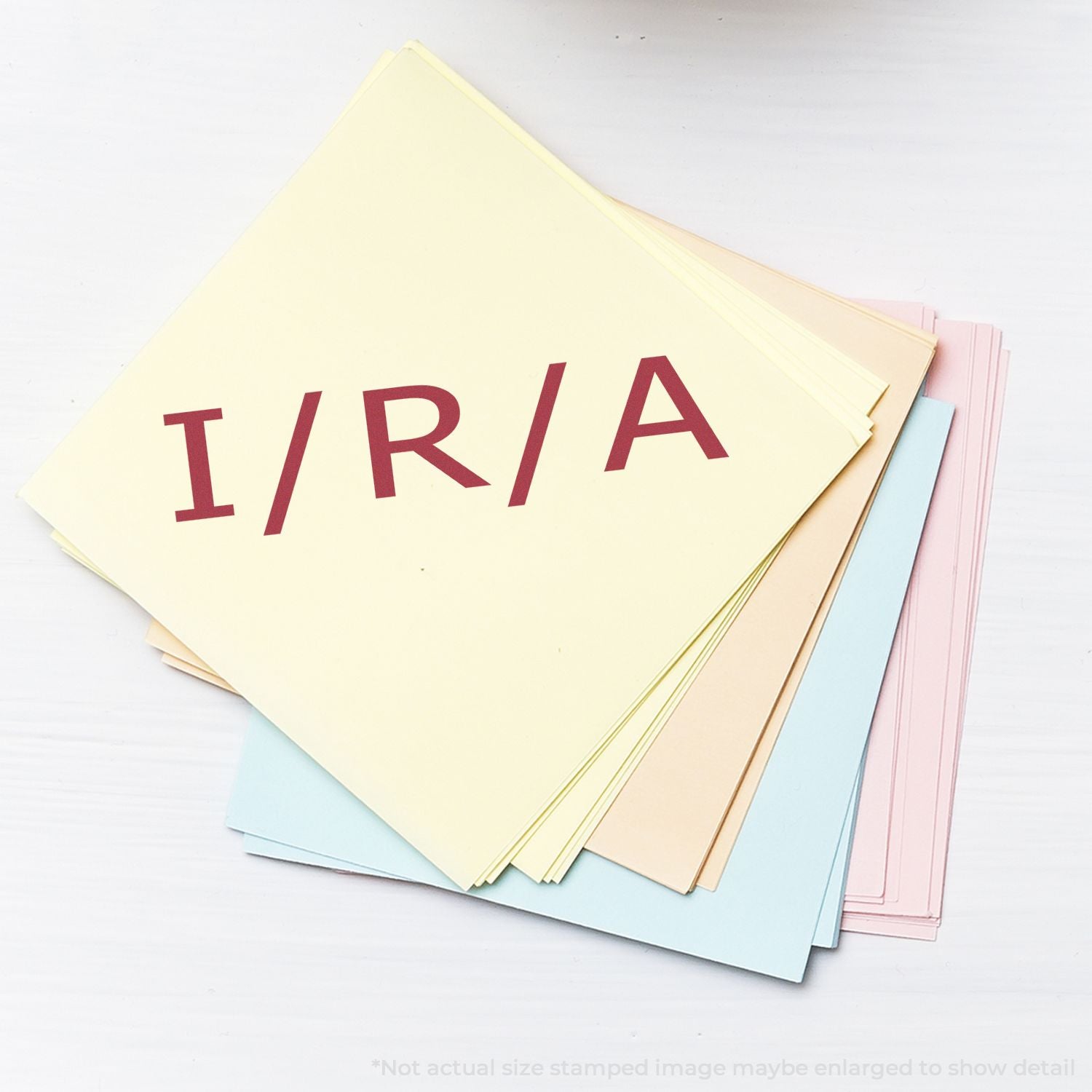 Stack of pastel colored paper sheets with I/R/A letters on top, office stationery on white background
