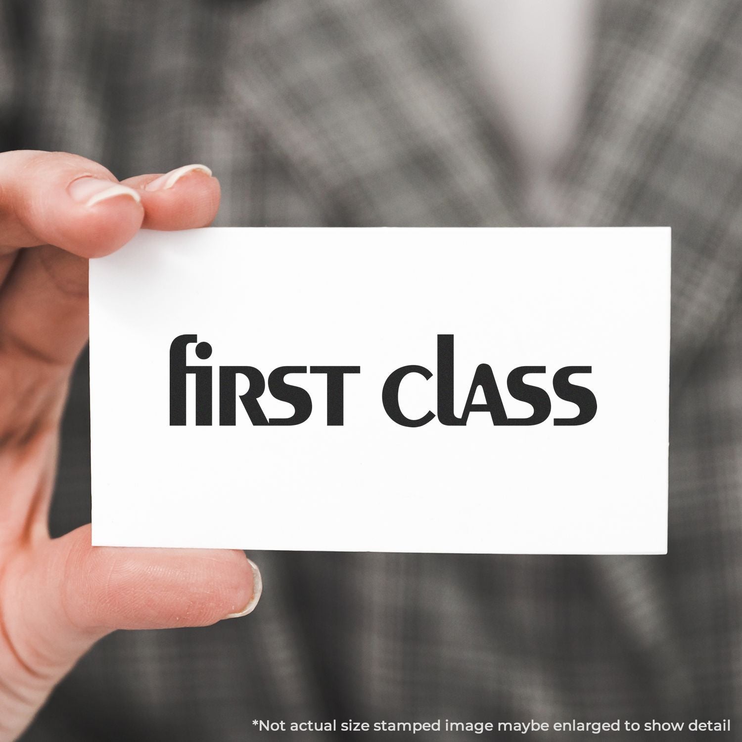 Hand holding a white business card with first class logo text on a blurred background.