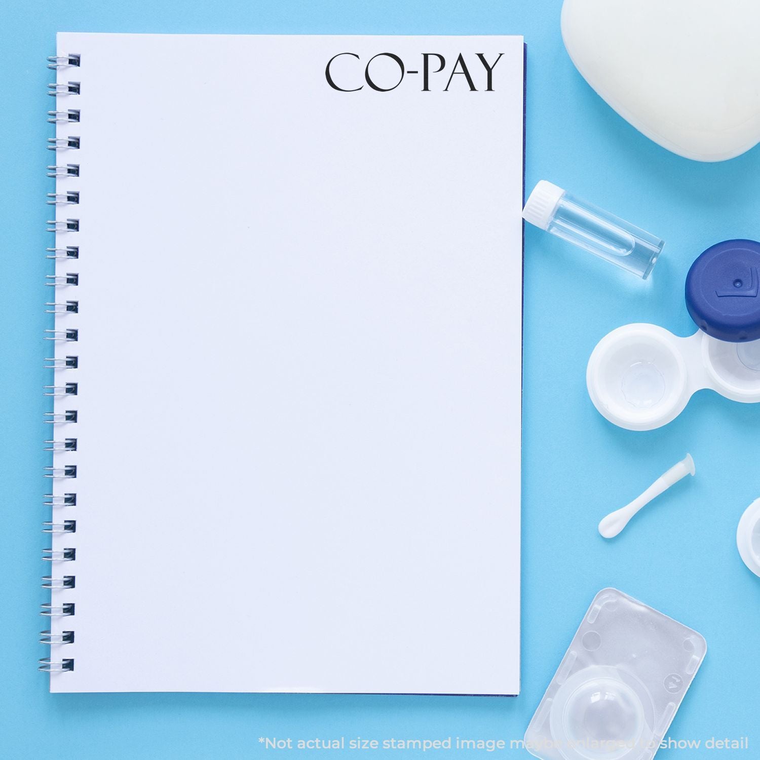 Optometry co-pay notebook with contact lens case, solution vial, and lens accessories on a blue background