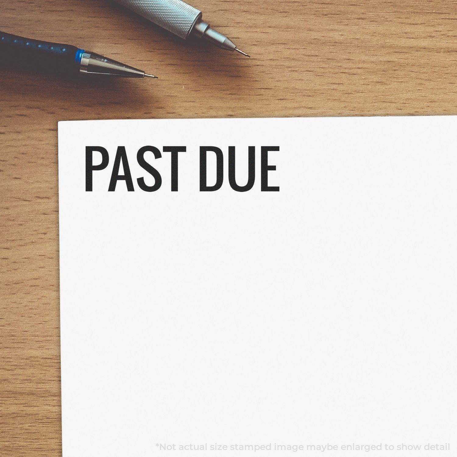 Past due payment reminder with pens on wooden desk, showing the text PAST DUE for overdue bills or invoices.