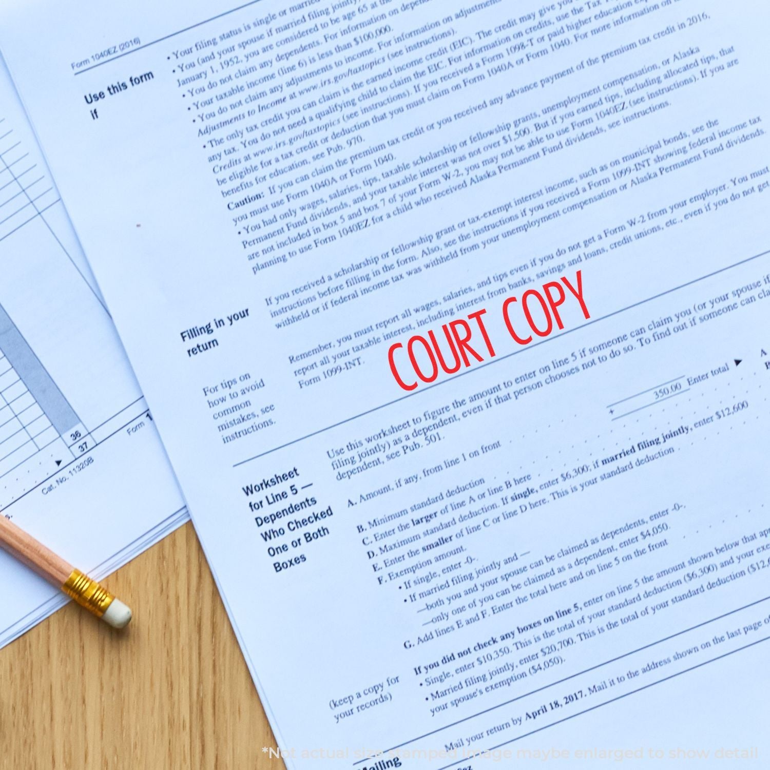 Close-up of a court copy tax form document on a wooden desk with a pencil, legal paperwork and IRS filing forms.