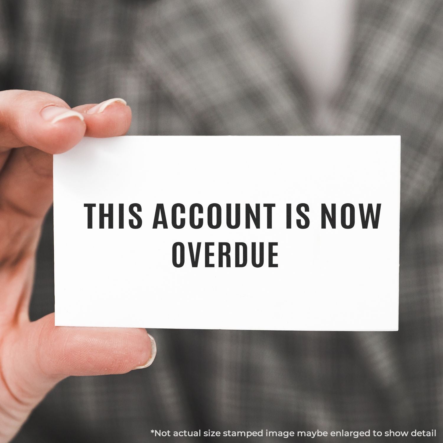 Hand holding a white card reading This account is now overdue, concept for overdue invoice and debt collection notice.