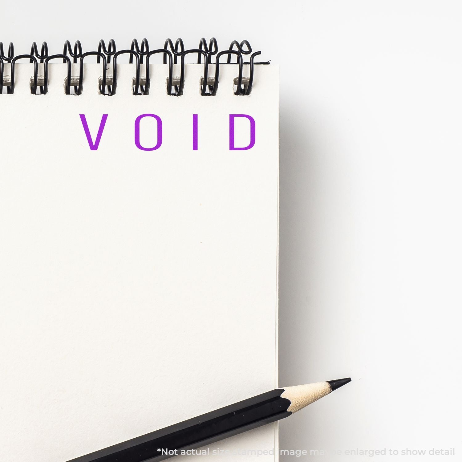 Blank spiral notebook with the word VOID in purple and a black pencil, minimalist stationery concept background.