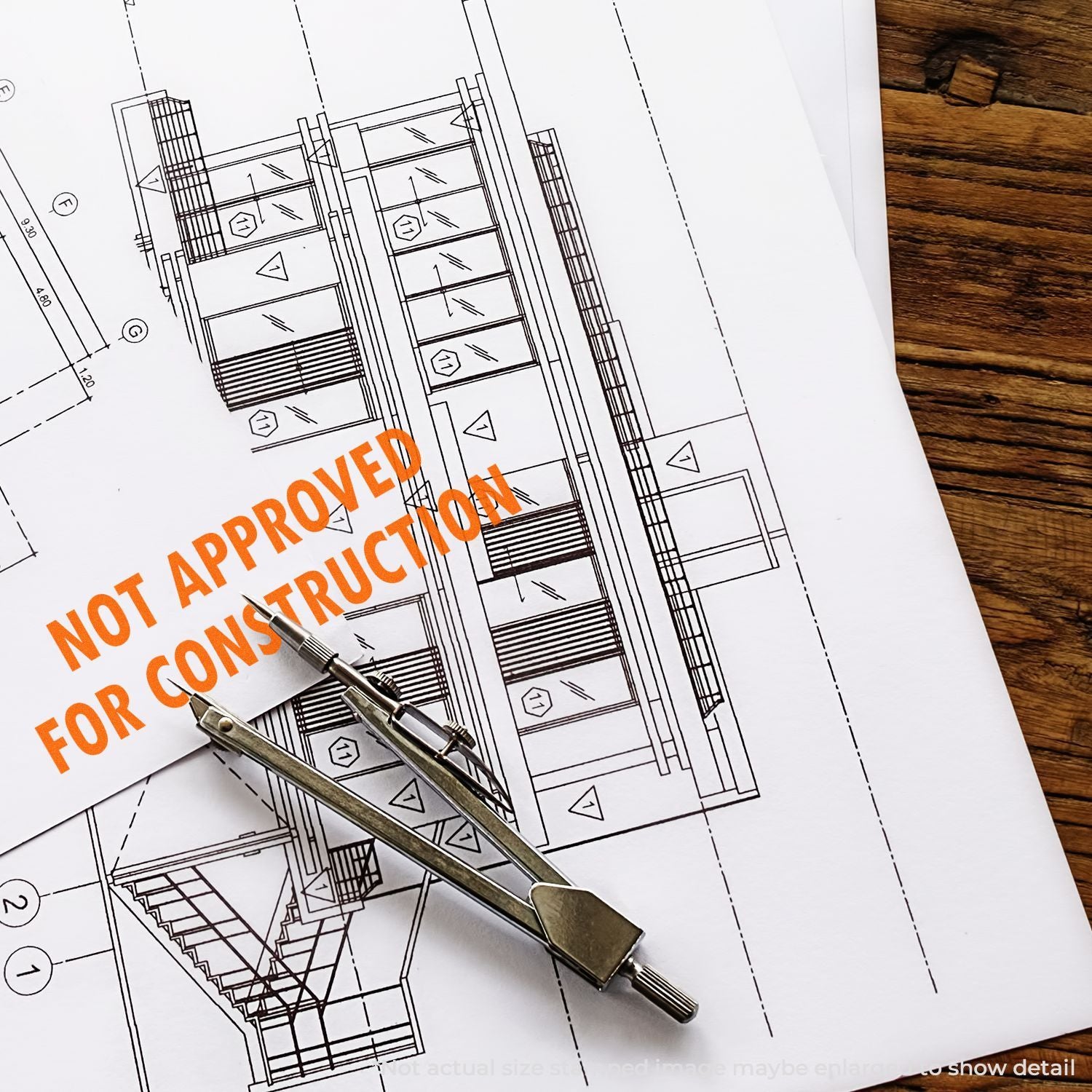 Architectural blueprint with construction stamp NOT APPROVED FOR CONSTRUCTION and metal drafting tool, indicating non-approved plans.