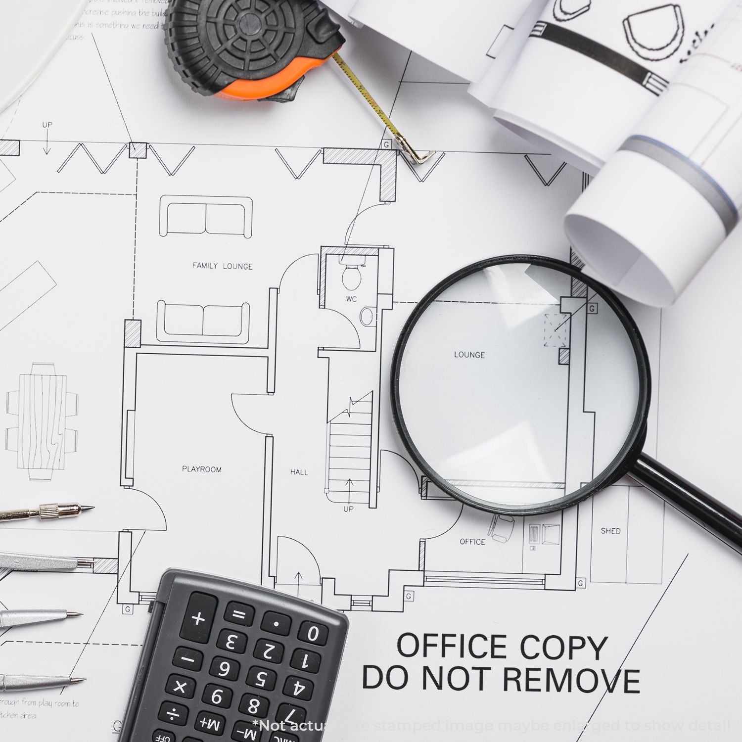 White floor plan blueprint with labeled rooms, calculator and magnifying glass, construction tape measure; office copy do not remove