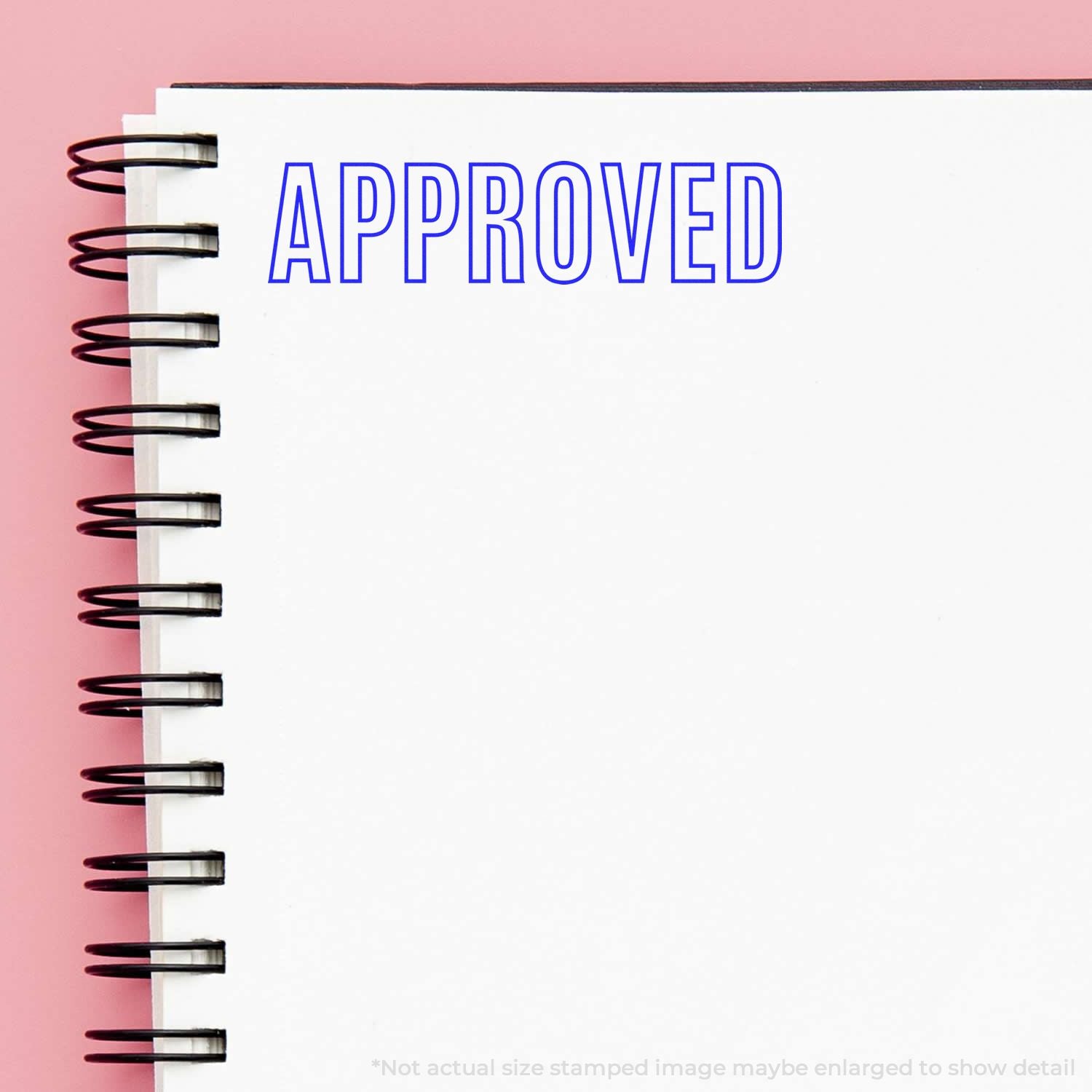 Approved stamp on a spiral notebook reading APPROVED, symbolizing paperwork authorization and verification.