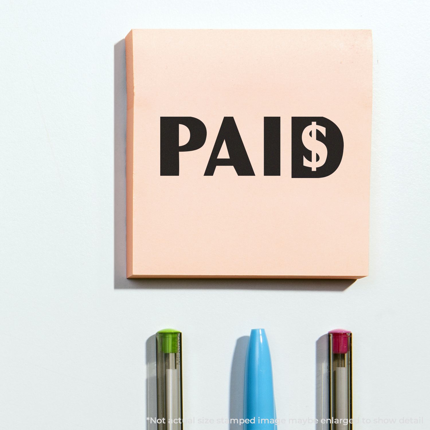 PAID stamp on peach notepad with pens, representing payment confirmation and settled invoices for bookkeeping and business finance