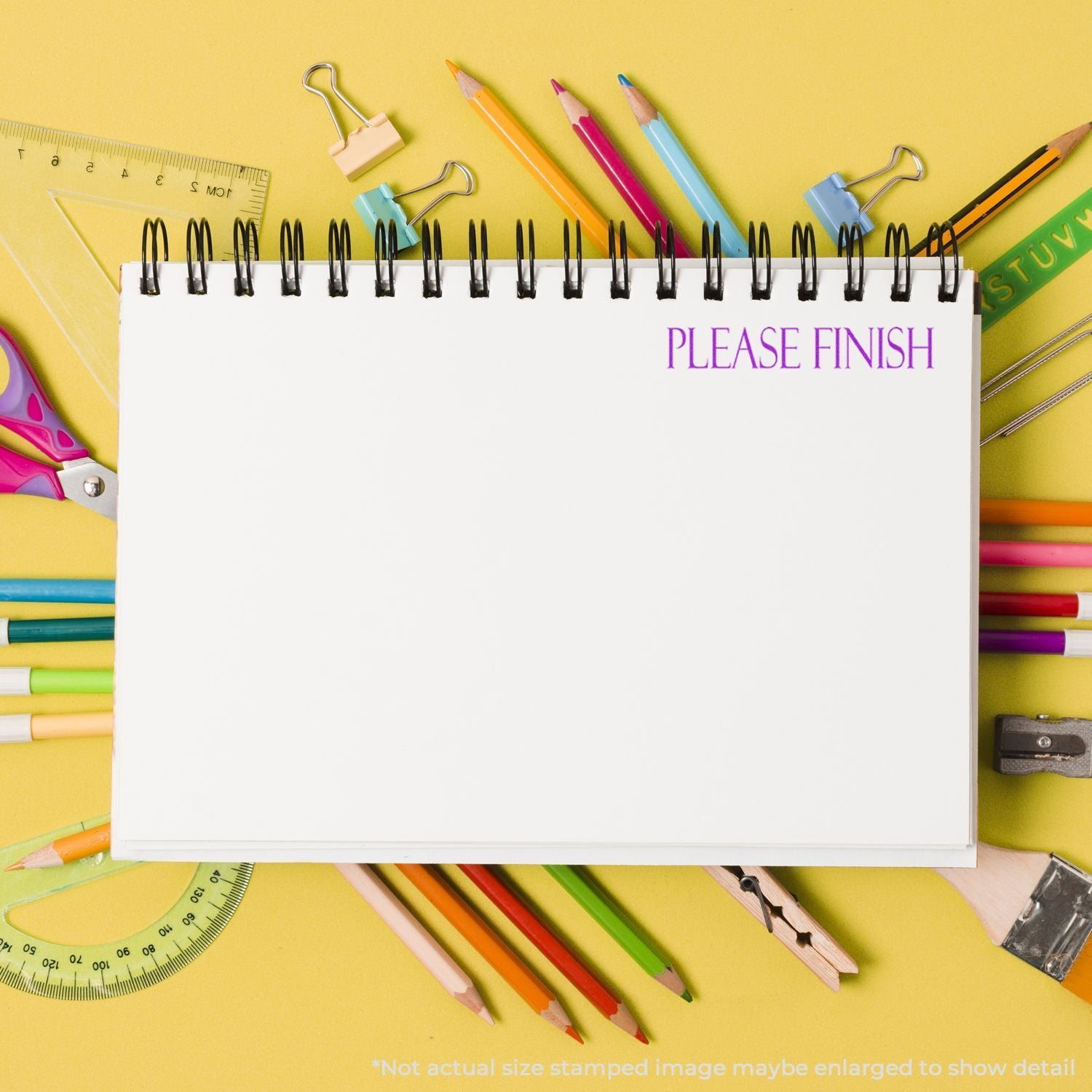 Top view of spiral notebook with Please Finish text surrounded by colorful school supplies on a yellow background.