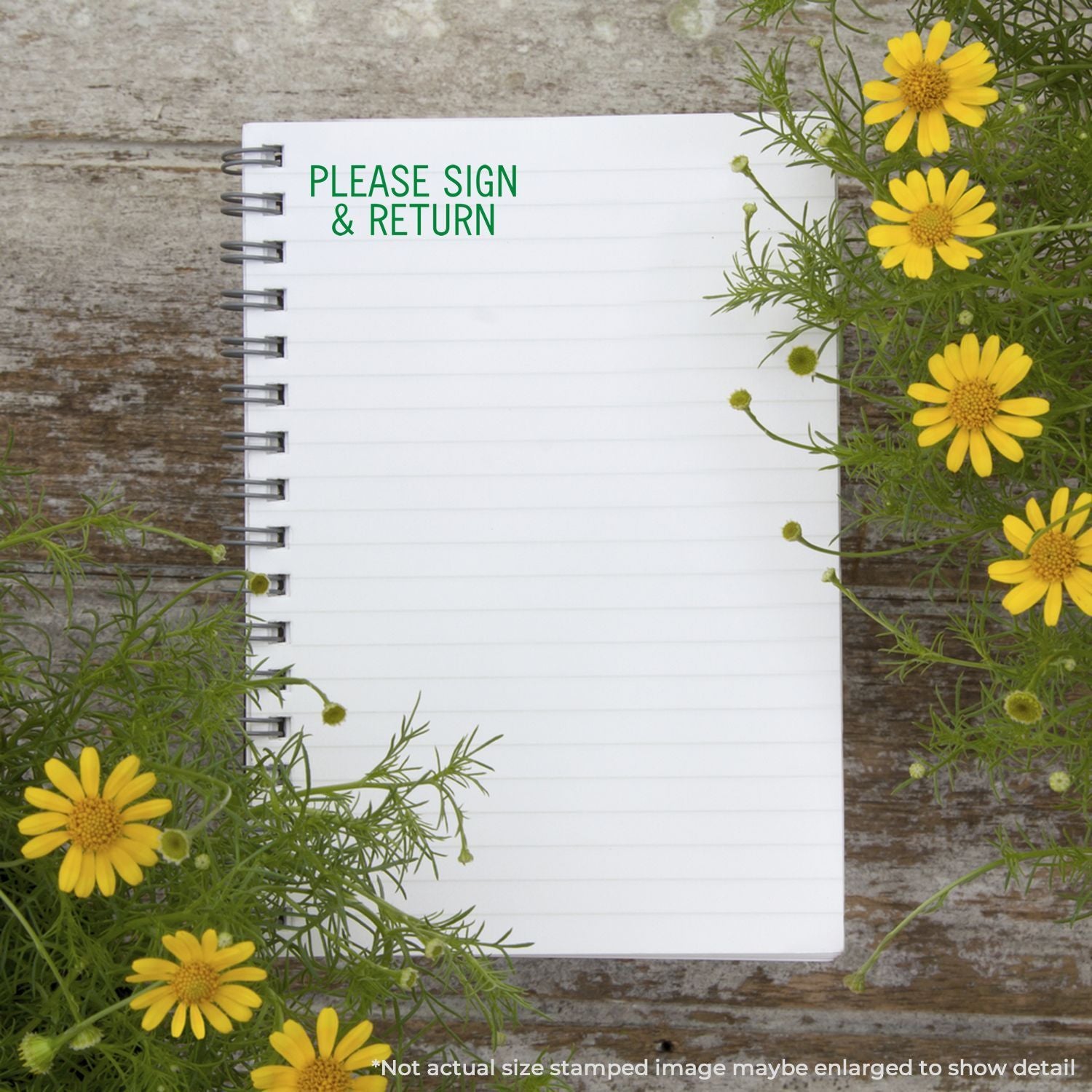 Notebook with Please Sign & Return text surrounded by yellow flowers on a rustic wooden background.