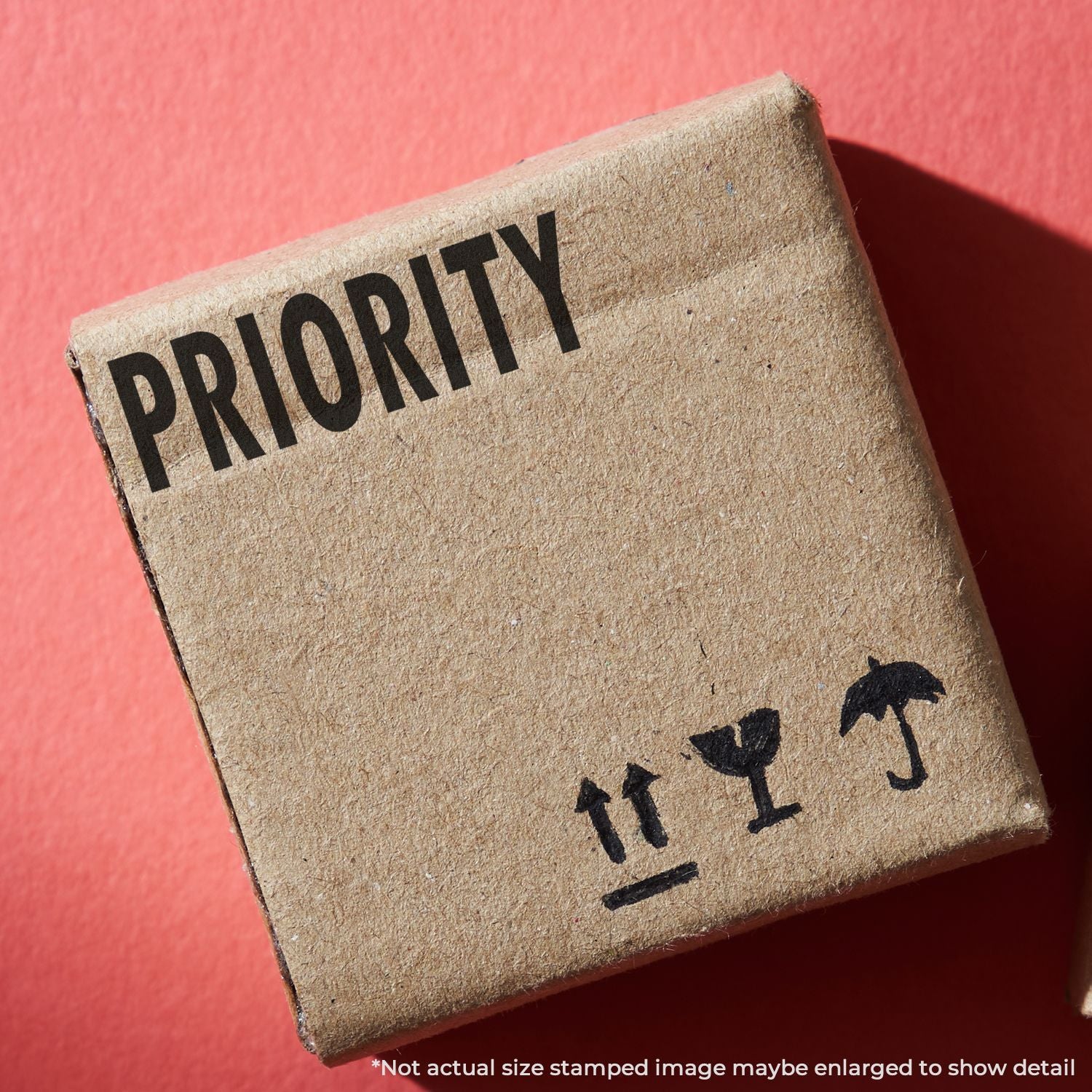 Priority shipping box on red background with fragile symbols printed on cardboard packaging.
