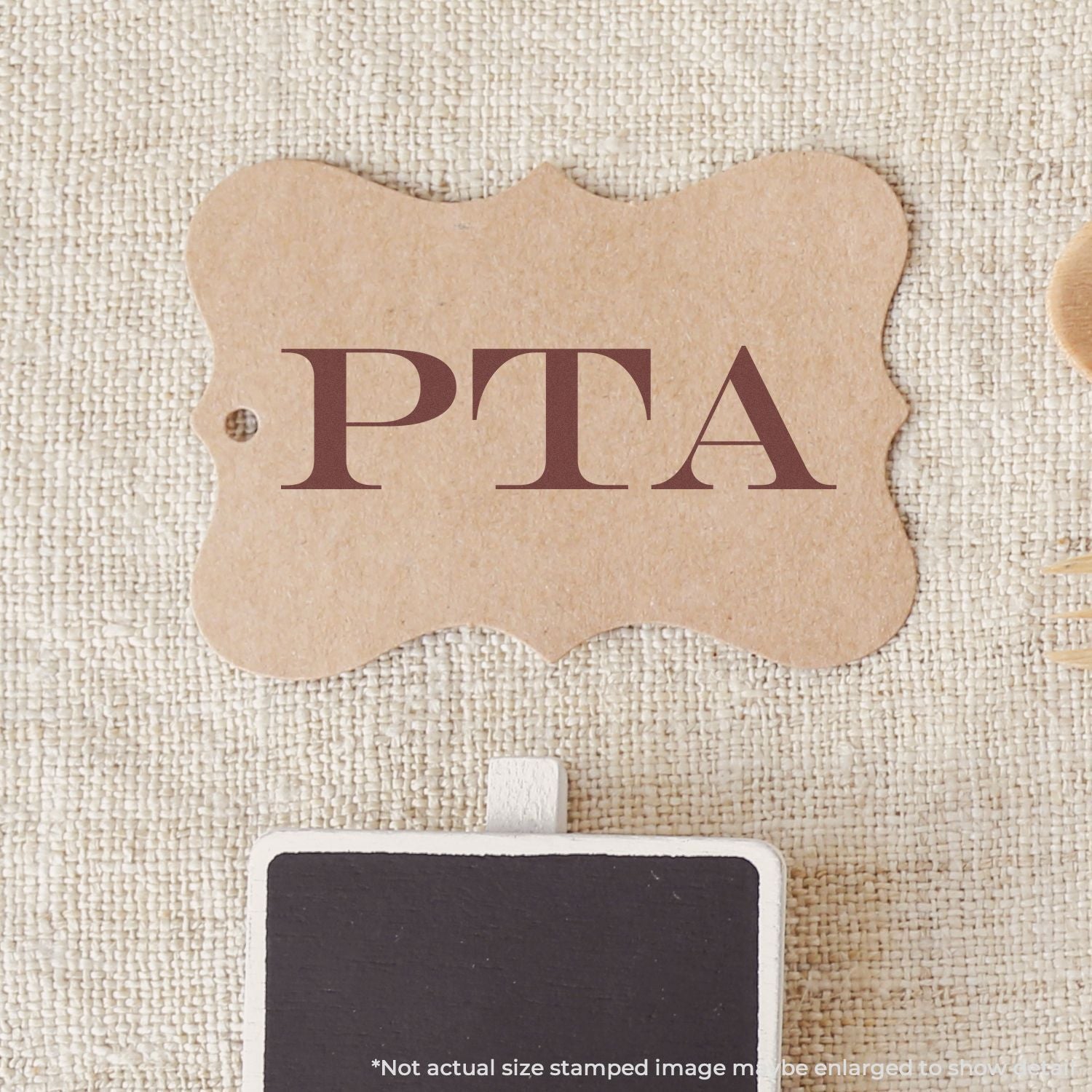 Kraft paper tag with printed PPA letters on beige woven fabric background, product label packaging image