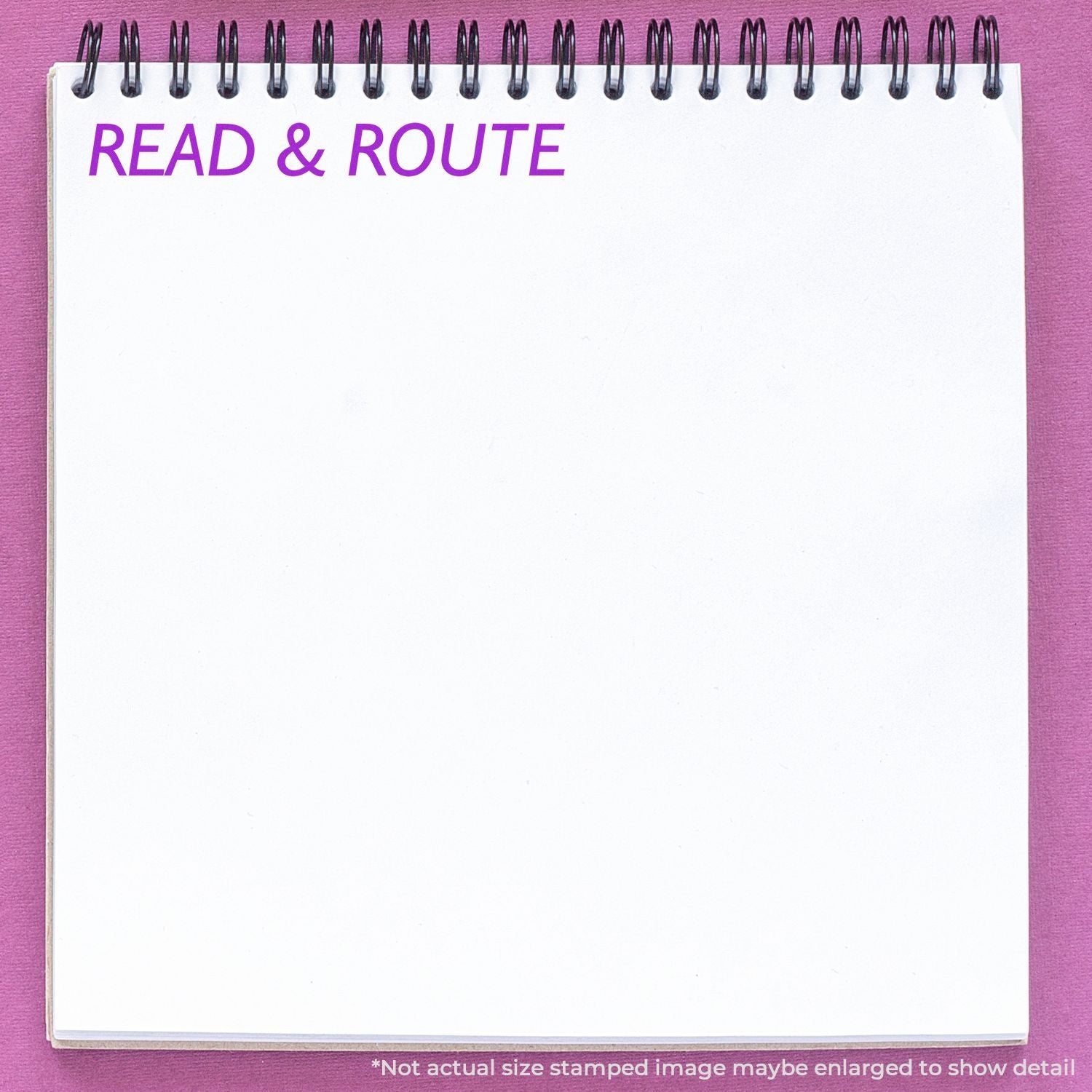 Spiral-bound notebook page on a pink background with purple text reading READ & ROUTE and blank writing space.