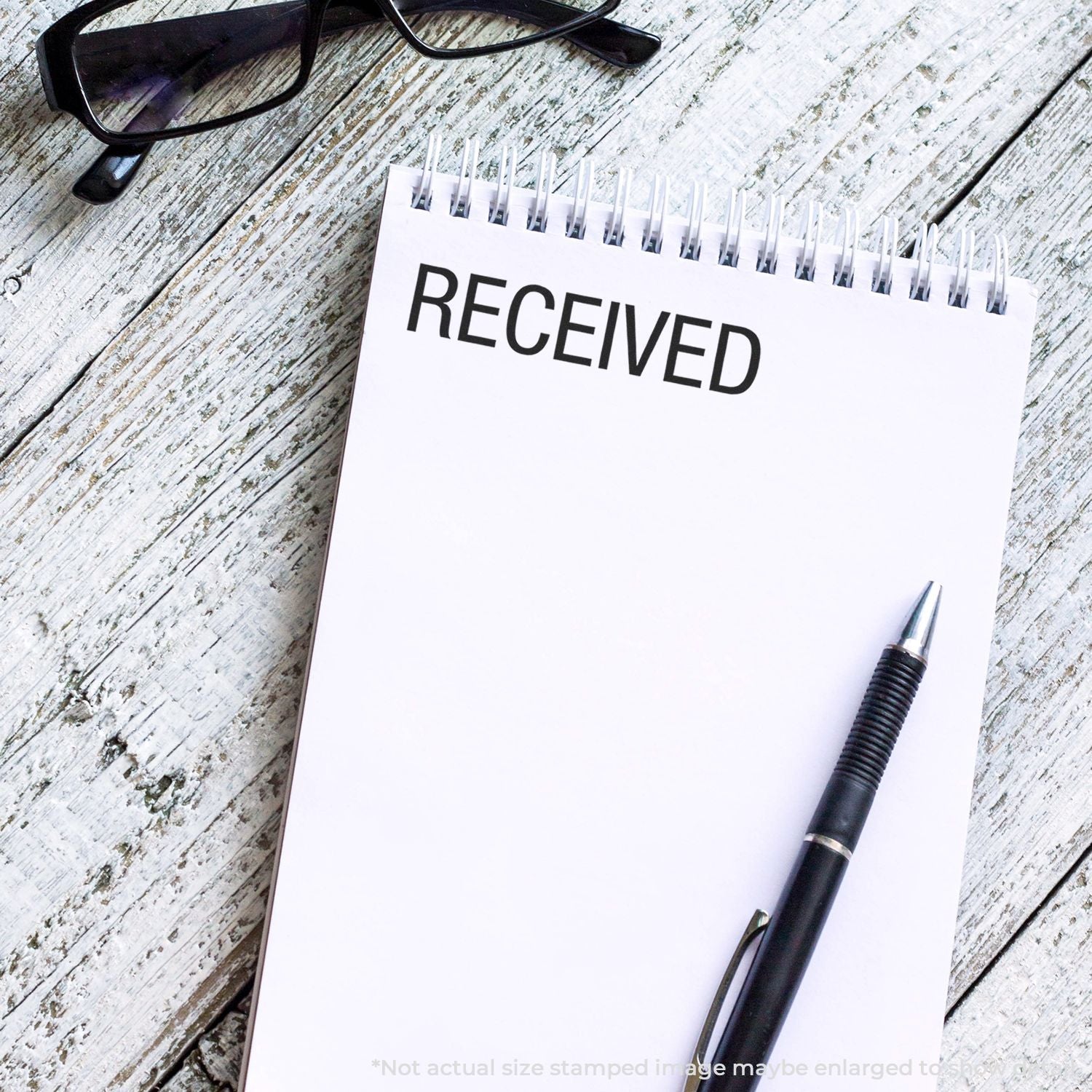 Received stamp on notepad with pen and glasses on weathered wood, symbolizing proof of document delivery and confirmation by mail.