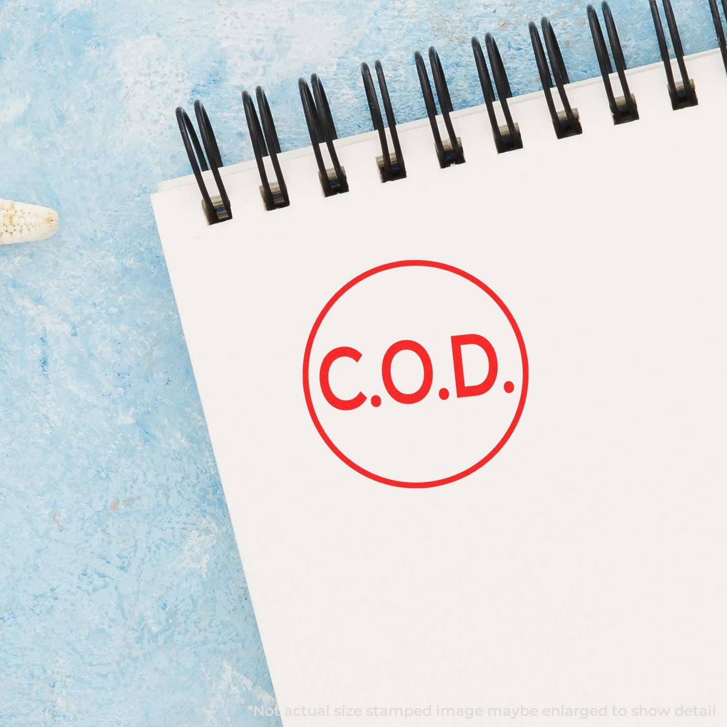 Red C.O.D. stamp on spiral notebook page, cash on delivery concept on a blue background.
