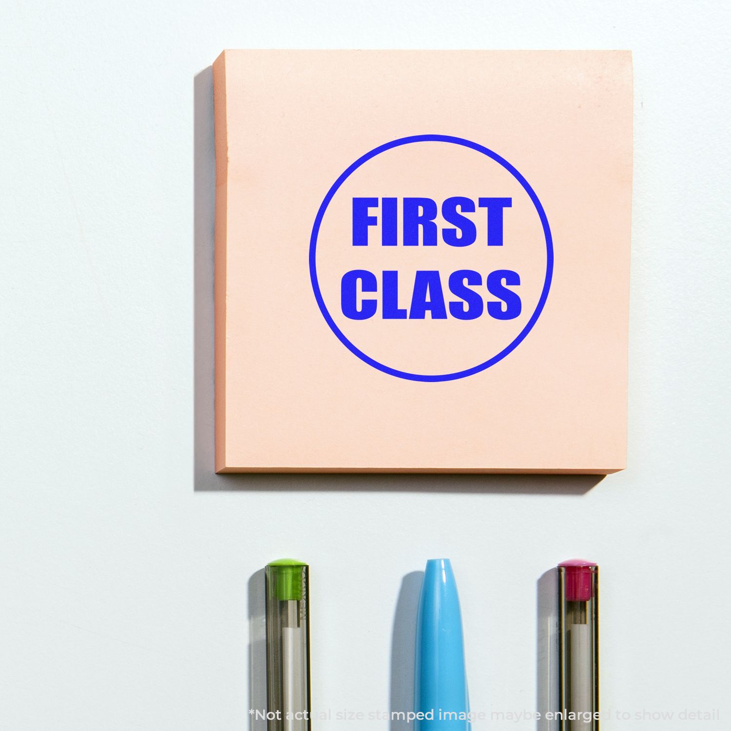 Minimalist first class wall art print with bold blue text on a beige background, paired with colorful pens on a white surface.