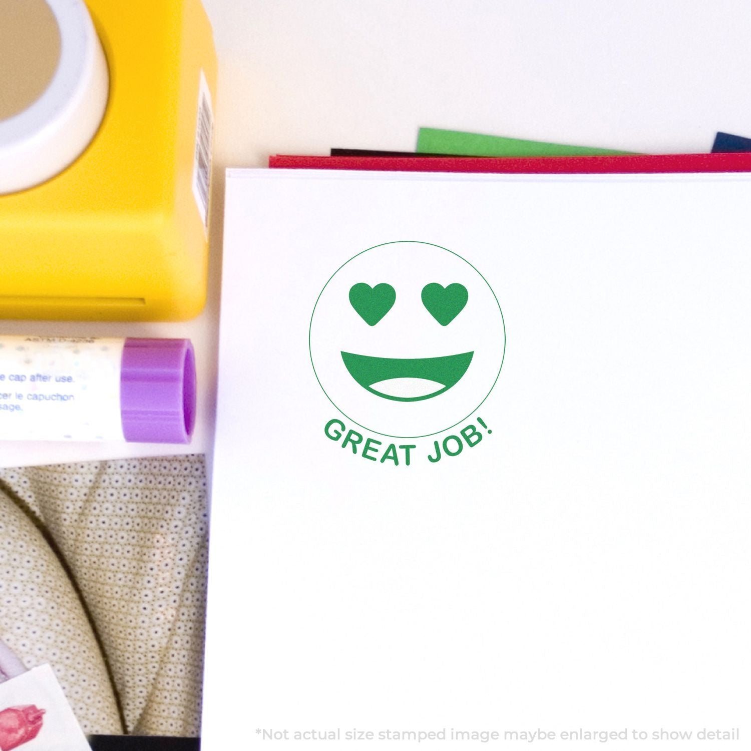 Great Job green heart-eyes smiley face stamp on white stationery with colorful office supplies.
