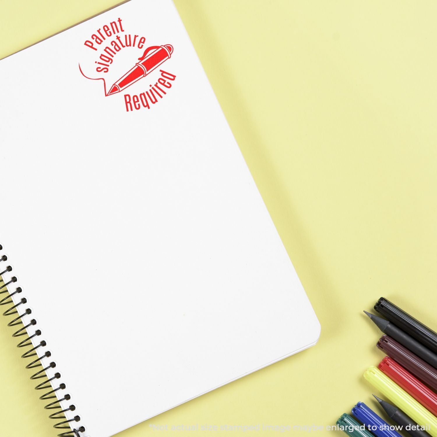 Blank spiral notebook with Parent Signature Required stamp and colorful markers on yellow background