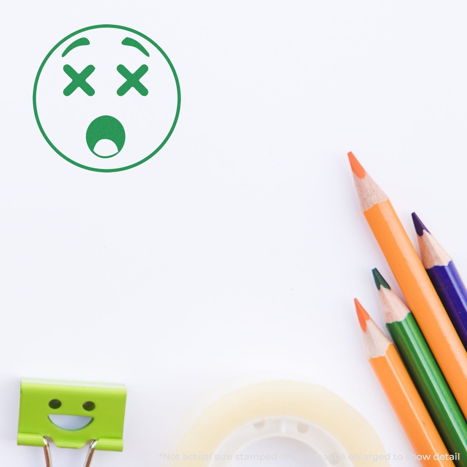 Colorful pencils and stationery on a white background with a green shocked emoji stamp and smiley paper clip.